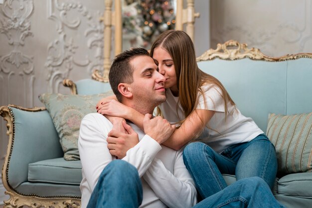 Umarmte Paare, die auf Sofa küssen