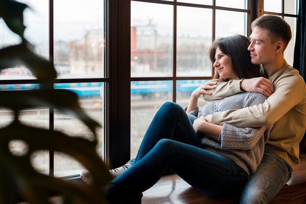 Umarmte Paare, die durch Fenster mit defocused Anlage schauen