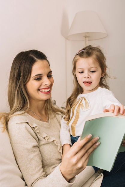 Umdrehenseiten des Mädchens des Buches beim Lesen mit Mutter