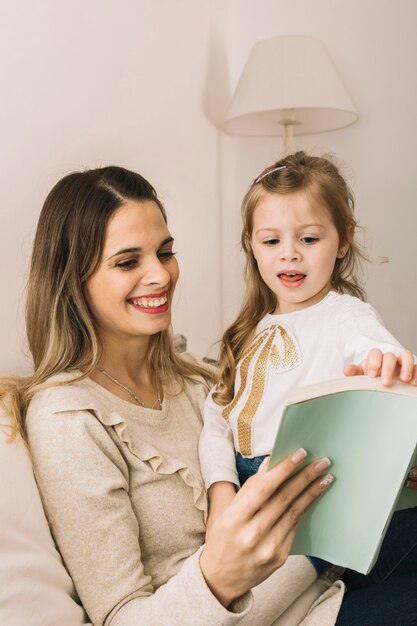 Umdrehenseiten des Mädchens des Buches beim Lesen mit Mutter