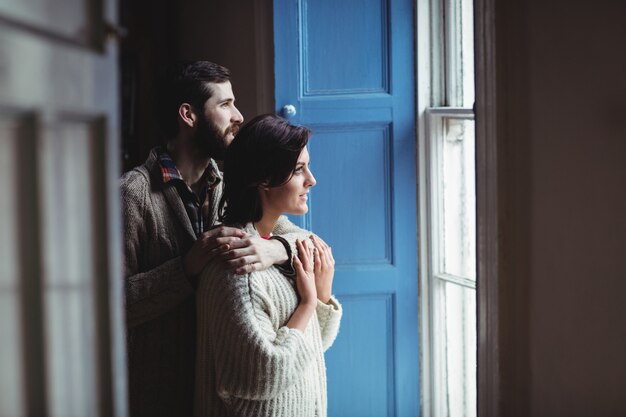 Umfassungsfrau des Mannes beim Schauen durch Fenster