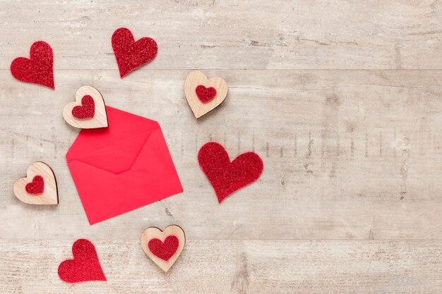 Umschlag für Valentinsgrüße mit Herzen auf hölzernem Hintergrund