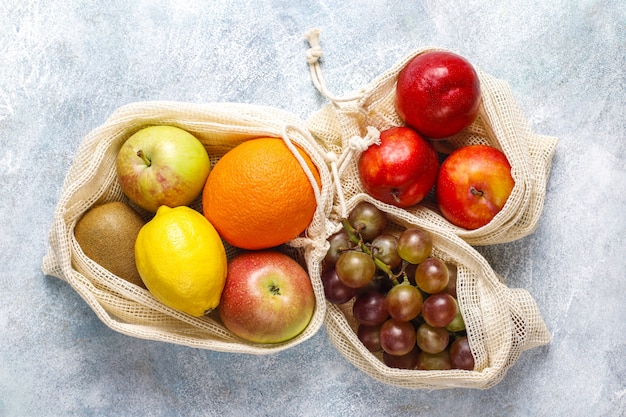 Umweltfreundliche, einfache Einkaufstaschen aus beiger Baumwolle zum Kauf von Obst und Gemüse mit Sommerfrüchten.