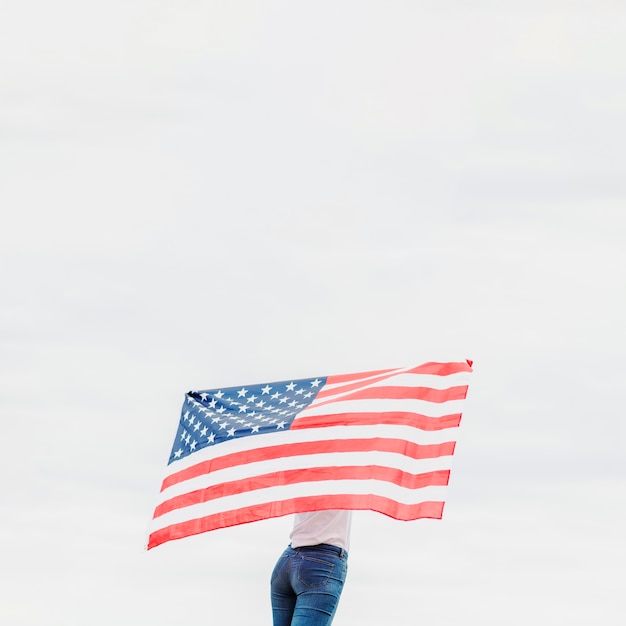 Unabhängigkeitstagkonzept mit der Frau, die Flagge auf Himmelhintergrund hält