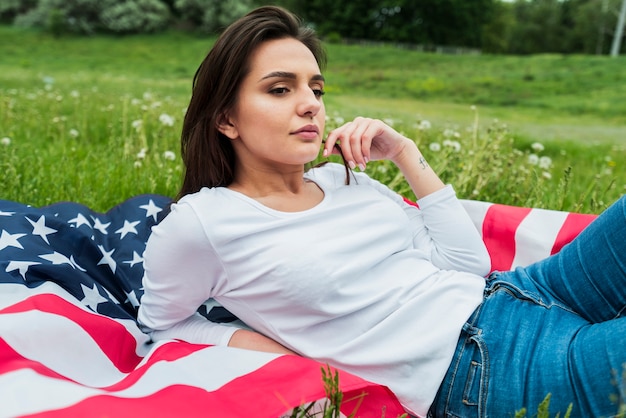 Kostenloses Foto unabhängigkeitstagkonzept mit frau und amerikanischer flagge auf gras