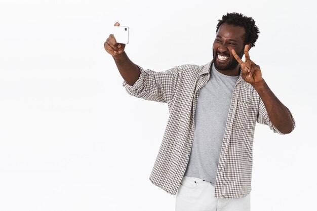 Unbeschwerter afroamerikanischer bärtiger Kerl reist ins Ausland und macht Selfies im Urlaub