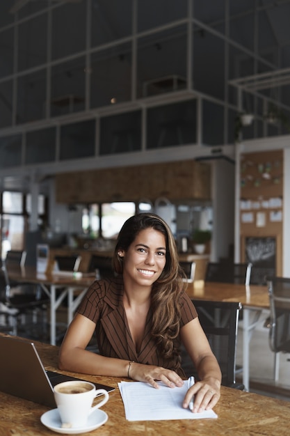 und erfolgreiche hispanische Frau lächelnd im Café arbeiten