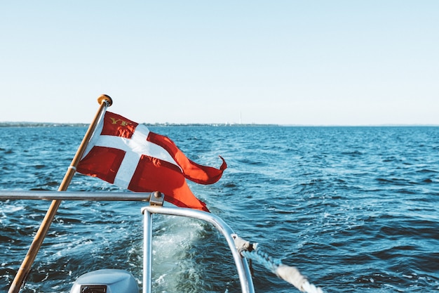 Und weiße Flagge auf einem Boot, das auf dem Ozean unter einem blauen Himmel während des Tages schwimmt