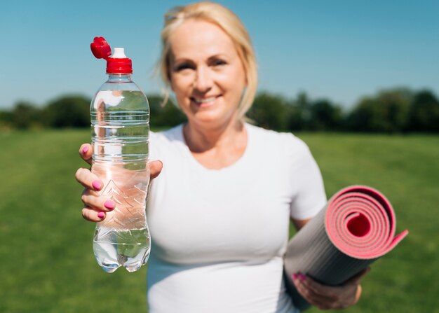 Undeutliche Frau der Vorderansicht, die Wasserflasche hält