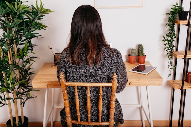 Kostenloses Foto unerkennbare frau, die am arbeitsplatz sitzt