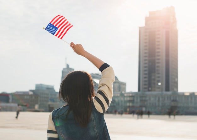 Unerkennbare Frau, die amerikanische Flagge am Unabhängigkeitstag wellenartig bewegt