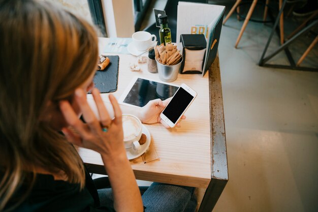 Unerkennbare Frau, die Smartphone im Café durchstöbert