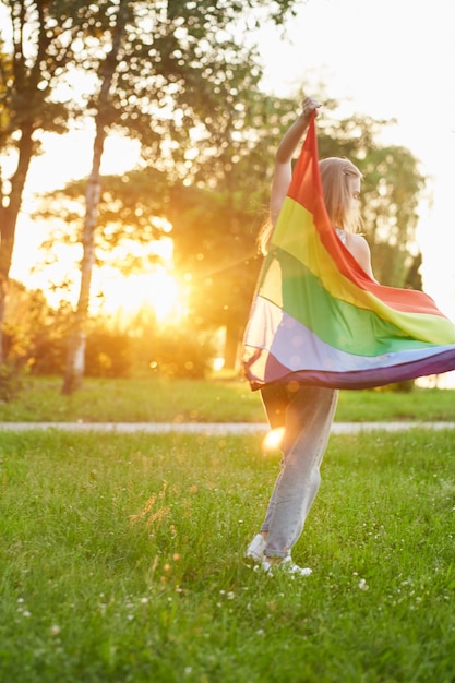 Unerkennbare Frau tanzt mit LGBT-Flagge hinter dem Rücken