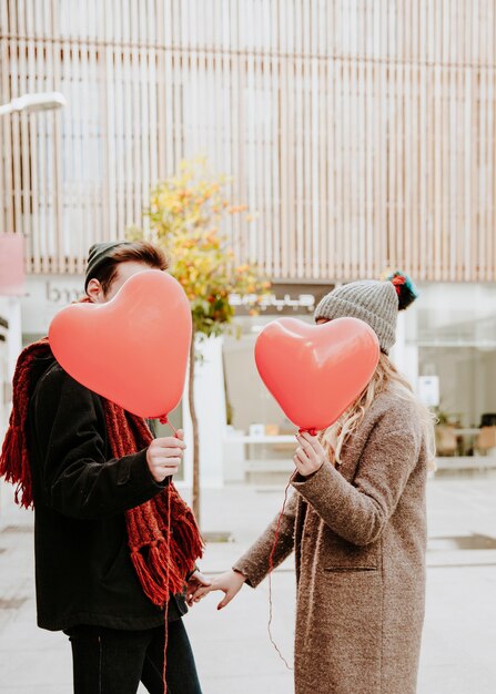 Unerkennbare Paare mit geformten Ballonen des Herzens
