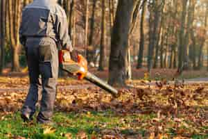 Kostenloses Foto unerkennbarer männlicher arbeiter mit blattbläser im stadtpark im rückblick auf einen starken mann