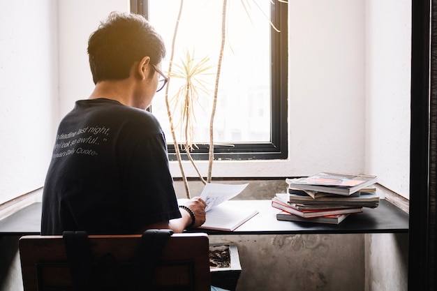 Unerkennbarer Mann, der nahe Fenster studiert