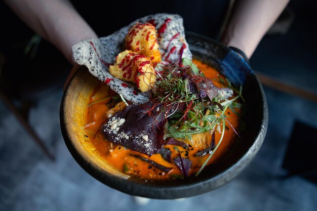 Unerkennbarer Mann isst asiatische Currysuppe mit Gemüse auf dunklem Hintergrund. Selektiver Fokus