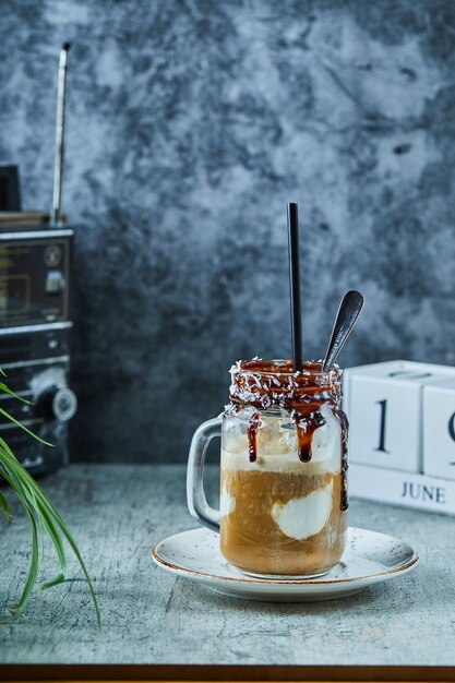 Unfertiger Milchshake mit Schokolade auf Becher mit Löffel