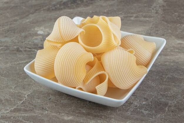 Ungekochte Conchiglie-Nudeln in weißer Schüssel