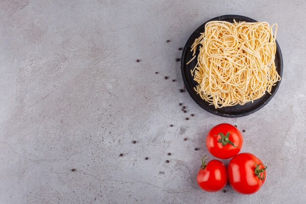 Ungekochte Instantnudeln mit frischen roten Tomaten und Pfefferkörnern.