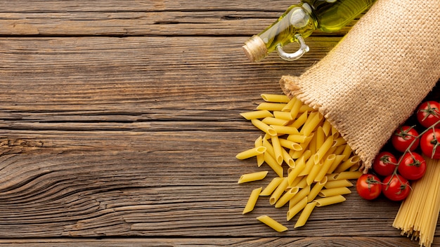 Ungekochte penne Tomaten und Olivenöl auf Holztisch mit Kopienraum