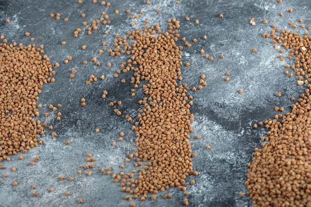 Kostenloses Foto ungekochter buchweizen auf marmoroberfläche verstreut