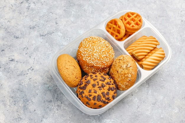 Ungesunde Brotdose mit Plätzchen, Waffeln Muffins auf Betondecke