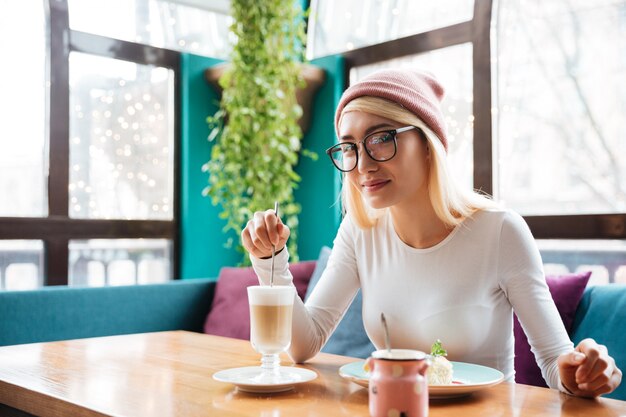 Unglaubliche junge Frau, die Kuchen isst und Kaffee trinkt