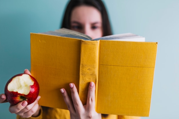 Unscharfe Frau mit Apfel und Buch