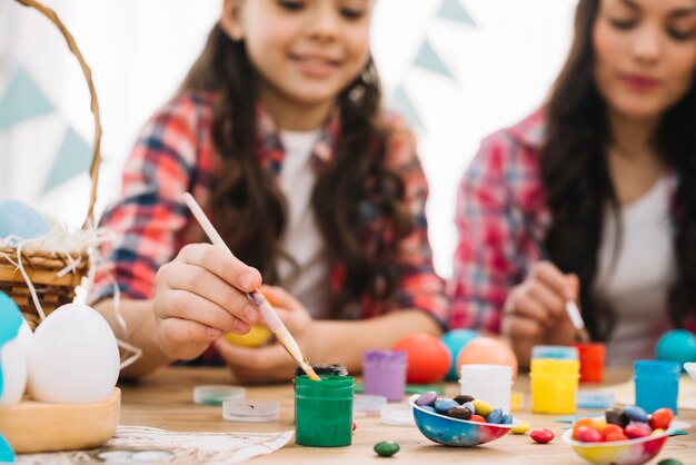 Unscharfe Mutter und Tochter, die die Ostereier über der Tabelle malen