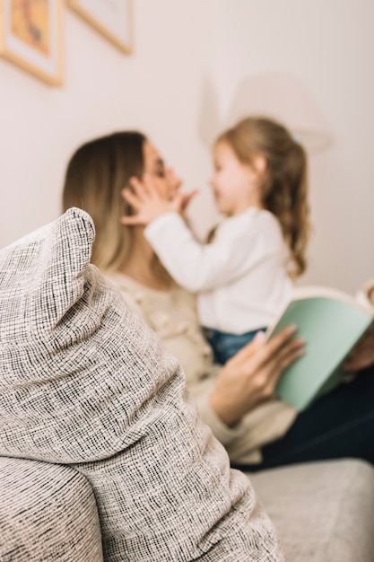 Unscharfe Tochter und Mutter, die Spaß lesen und haben