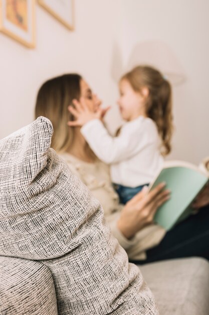 Unscharfe Tochter und Mutter, die Spaß lesen und haben