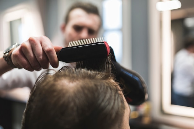 Unscharfer Friseur, der Haar des Kunden anredet