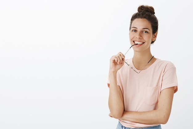 Unsicheres nachdenkliches Mädchen mit Brille, die gegen die weiße Wand aufwirft