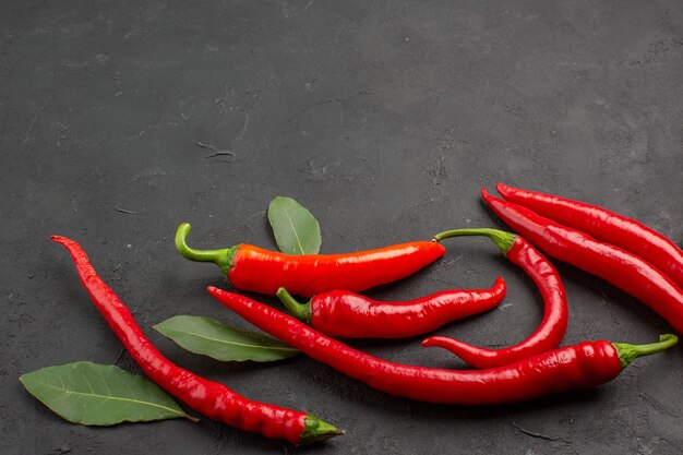 Unten Ansicht rote Paprika und Lohnblätter am unteren Rand des schwarzen Hintergrunds