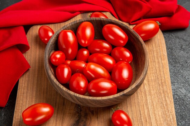 Unten nahe Ansicht Schüssel mit Kirschtomaten und rotem Handtuch auf einem Schneidebrett auf dunklem Hintergrund