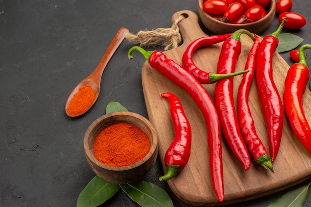 Kostenloses Foto unten sehen sie eine schüssel mit kirschtomaten und rotem paprika auf der schneidebrettbucht. sie hinterlassen einen holzlöffel und eine schüssel ketchup auf dem schwarzen tisch