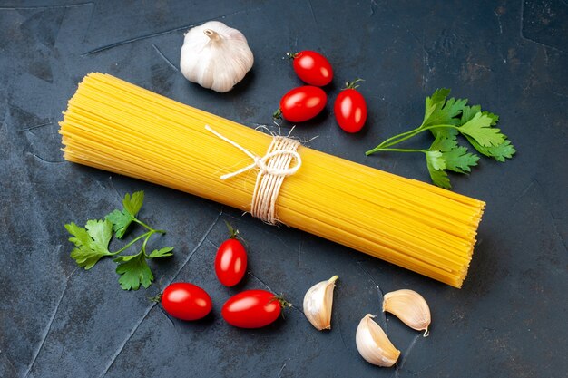 Unteransicht Bündel Sphaggeti Kirschtomaten Knoblauch Petersilie auf dunklem Tisch