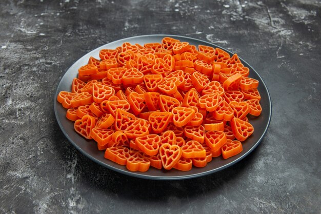 Unteransicht herzförmige italienische Pasta auf schwarzer ovaler Platte auf dunkler Oberfläche