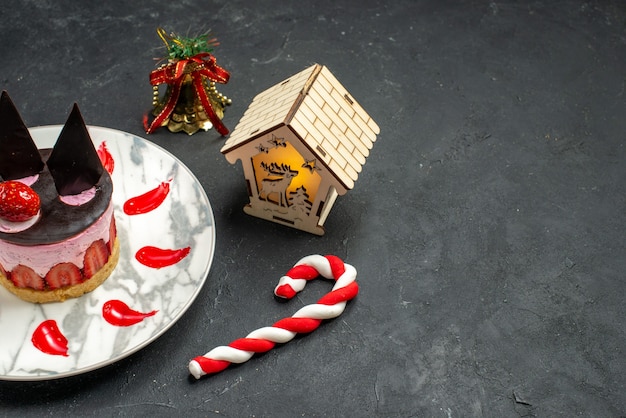 Unteransicht köstlicher Käsekuchen mit Erdbeeren und Schokolade auf ovalem Teller Weihnachtsspielzeug auf dunklem Hintergrund