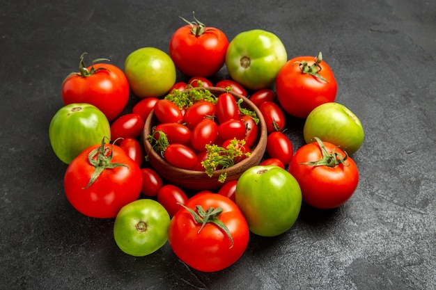 Untere Ansicht Kirschrot und grüne Tomaten um eine Schüssel mit Kirschtomaten auf dunklem Hintergrund