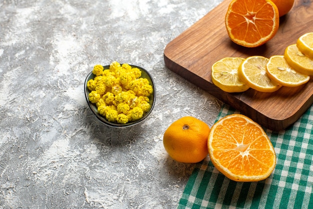 Untere Hälfte Ansicht Orangen Zitronenscheiben auf Holzbrett gelbe Bonbons in Schüssel auf grauer Oberfläche