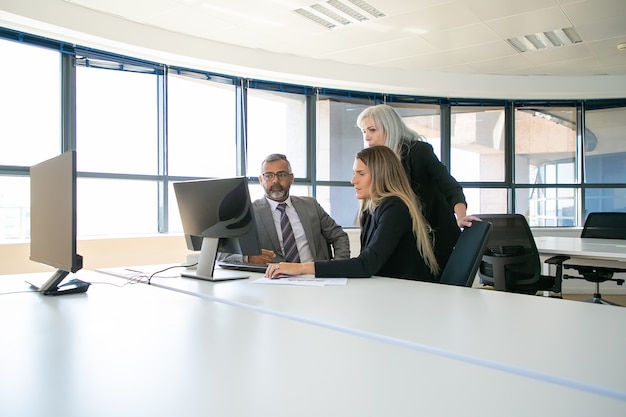 Unternehmensmanager diskutieren Lösung. Geschäftsleute versammeln sich im Besprechungsraum und schauen sich gemeinsam Inhalte auf dem Computermonitor an. Geschäftskommunikations- oder Teamwork-Konzept