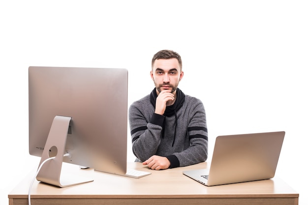 Unternehmer, der am Tisch mit Laptop und Personalcomputer sitzt und Kamera lokalisiert auf Weiß betrachtet