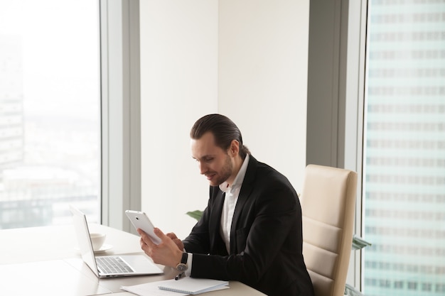 Unternehmer, der Tablette beim Sitzen am Schreibtisch verwendet