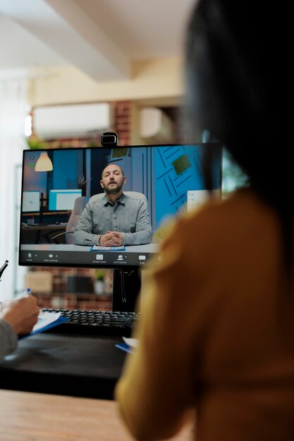 Unternehmerin, die den Lebenslauf des Personalvermittlers liest und die Einstellungsbewerbung mit einem potenziellen Remote-Arbeiter während einer Online-Videoanruf-Konferenz im Startup-Büro bespricht. Telefonkonferenz auf dem Computerbildschirm