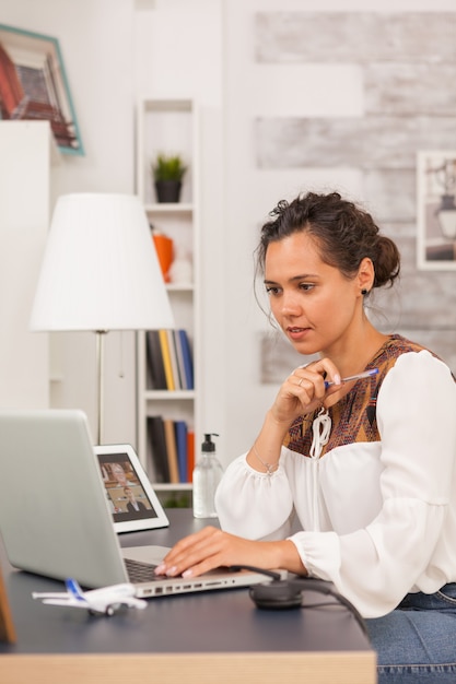 Unternehmerin, die Laptop während der Arbeit vom Home Office betrachtet.