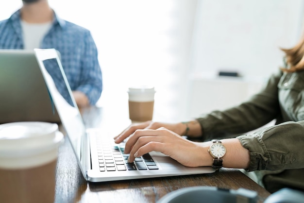 Unternehmerin mit Laptop am Schreibtisch, während sie mit Kollegen im Büro arbeitet