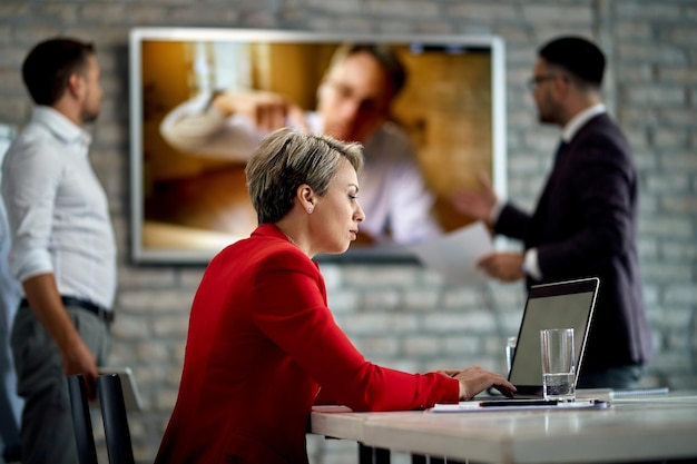 Unternehmerin mit Laptop beim Geschäftstreffen mit ihrem Kollegen im Büro