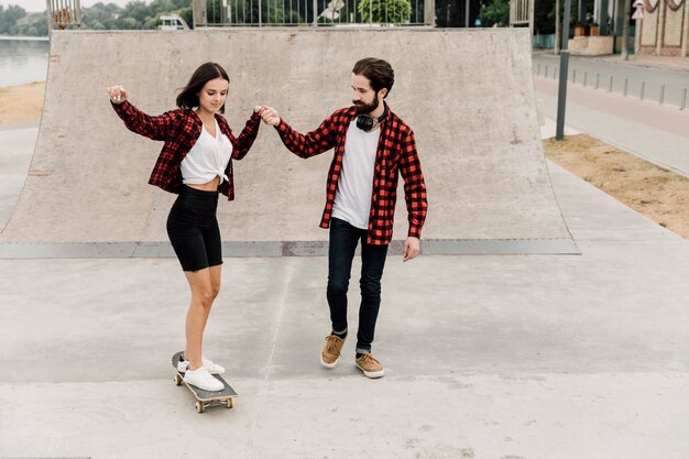 Unterrichtende Freundin des Mannes, zum eines Skateboards zu reiten